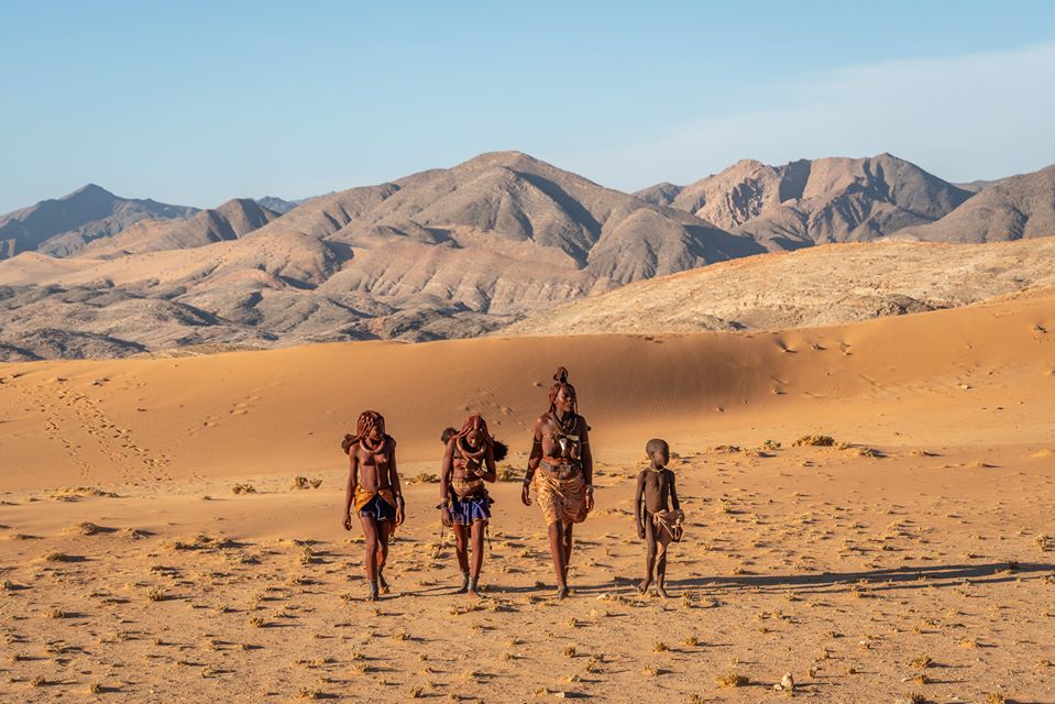 Himba lady and three young girls walking in the desert